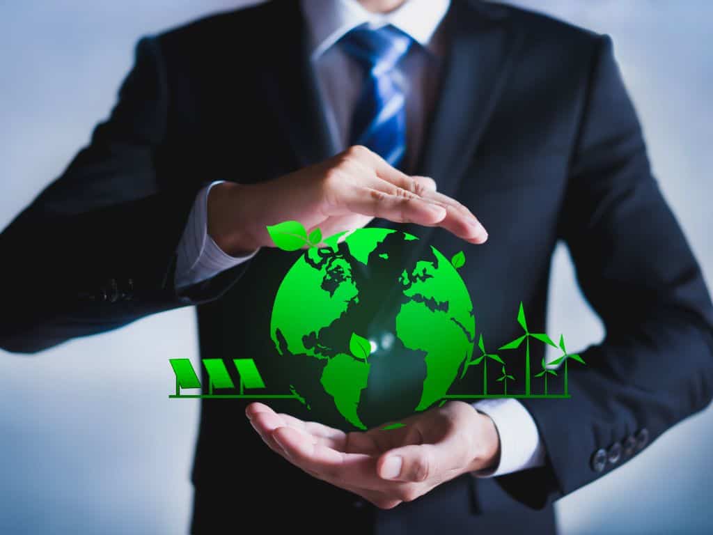 A businessman holding a green globe representing environmentally friendly practises.